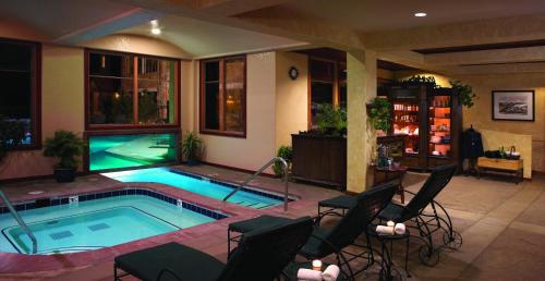 a swimming pool in a room with chairs around it at Fairmont Heritage Place, Franz Klammer Lodge in Telluride