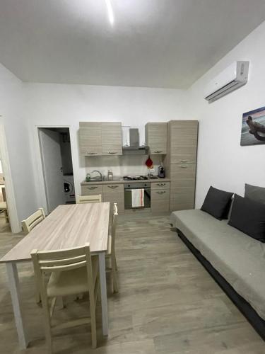 Casa Marianelli في كالابيرناردو: مطبخ وغرفة معيشة مع طاولة وأريكة