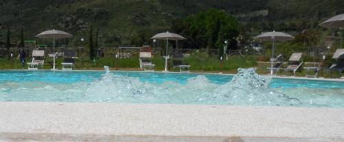 einen Pool mit Wasser, Stühlen und Sonnenschirmen in der Unterkunft Il Sentiero di Leano in Terracina