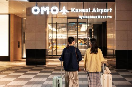two people walking in front of a store with luggage at OMO Kansai Airport by Hoshino Resorts in Izumi-Sano