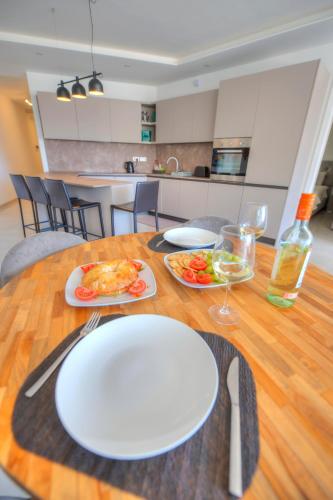 a wooden table with white plates of food on it at Seaside apartment in the heart of Xlendi Gozo in Xlendi