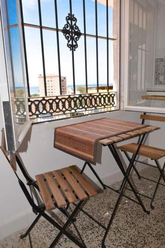 una mesa y un banco en un balcón con ventana en Casita con mirador, en Málaga