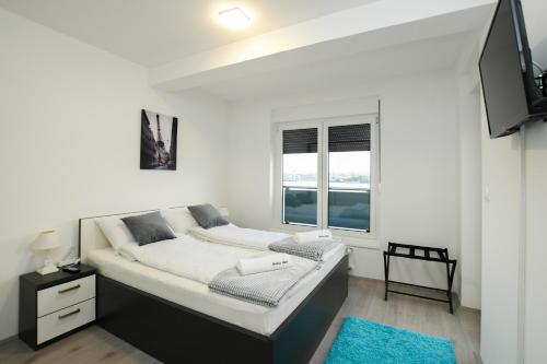 - une chambre blanche avec un lit et une fenêtre dans l'établissement Apartman Klara, à Kladovo