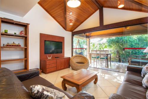 a living room with a couch and a tv at Praia da Ferradura com quatro suítes e piscina. in Búzios