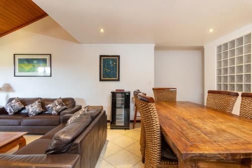 uma sala de estar com uma mesa de madeira e um sofá em Praia da Ferradura com quatro suítes e piscina. em Búzios