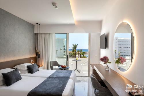 a hotel room with a bed and a large window at Pavlo Napa Beach Hotel in Ayia Napa
