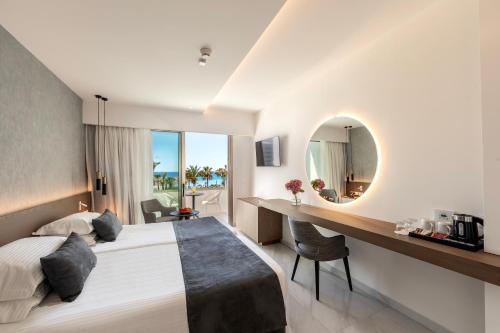 a bedroom with a bed and a desk and a mirror at Pavlo Napa Beach Hotel in Ayia Napa