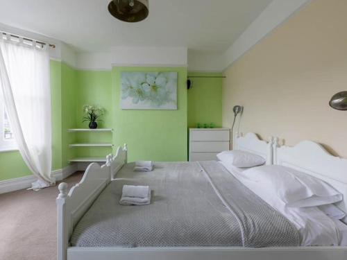 a bedroom with a white bed and green walls at Cute and Cosy 2 Bed on a Peaceful street in Kent