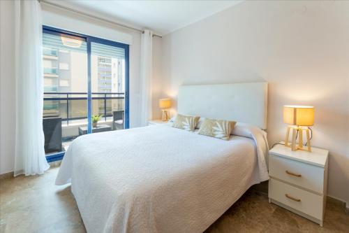 een slaapkamer met een wit bed en een groot raam bij AG RESIDENCIAL EL EDEN in Playa de Gandia