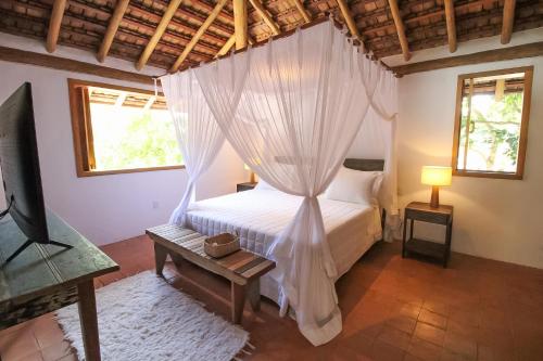 a bedroom with a bed with a mosquito net at Pousada Outeiro in Praia do Espelho