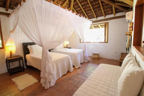 a bedroom with two beds with white sheets at Pousada Outeiro in Praia do Espelho