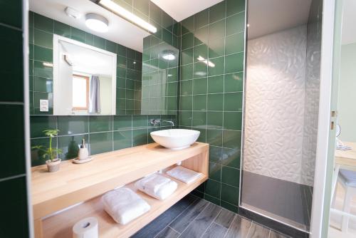 Baño de azulejos verdes con lavabo y espejo en L’AZIMUT, en Senez