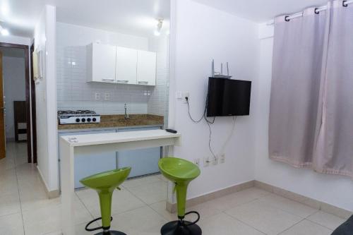 a kitchen with a sink and two green stools at Jardins do Atlântico in João Pessoa