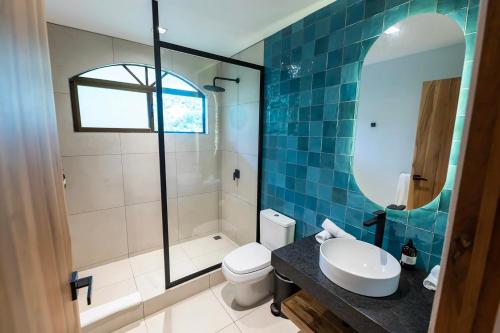 a bathroom with a toilet and a sink and a mirror at Marala Hotel in Esterillos