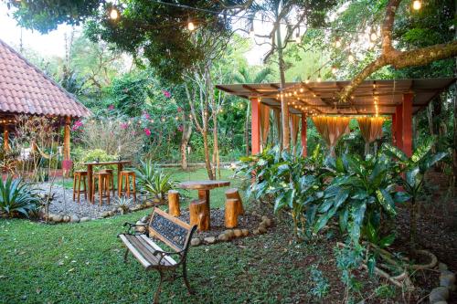 a garden with a bench and a wooden pergola at Naturalmente Boutique Bungalows y Cocina Mediterránea in Las Lajas