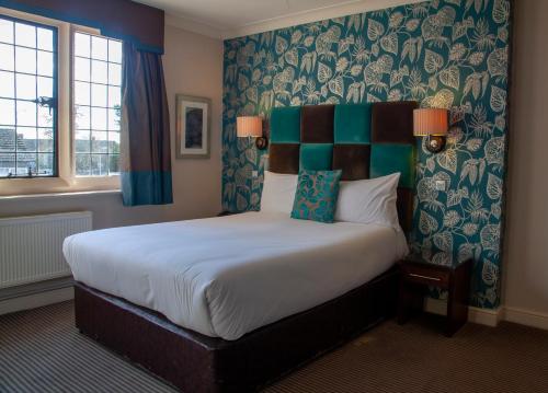 a bedroom with a large bed with blue and green wallpaper at Hopping Hare in Northampton