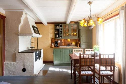 a kitchen with green cabinets and a table with chairs at Torppa Stengård 1700-luvulta in Porvoo