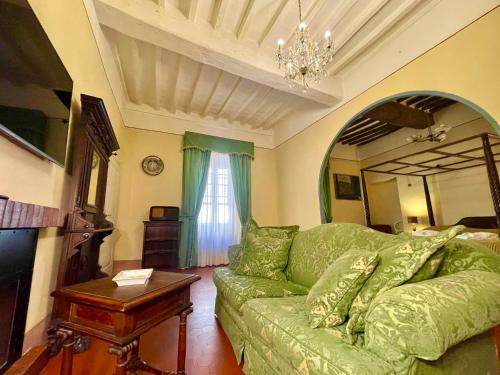 a living room with a green couch and a table at Palazzo Barbini Dimora Storica in Castiglione del Lago