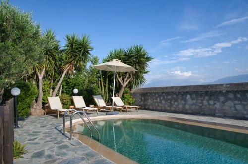 a swimming pool with chairs and an umbrella at Villa Athina in Megála Khoráfia