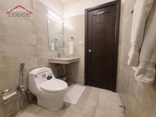 a white bathroom with a toilet and a sink at Embassy Lodge in Islamabad
