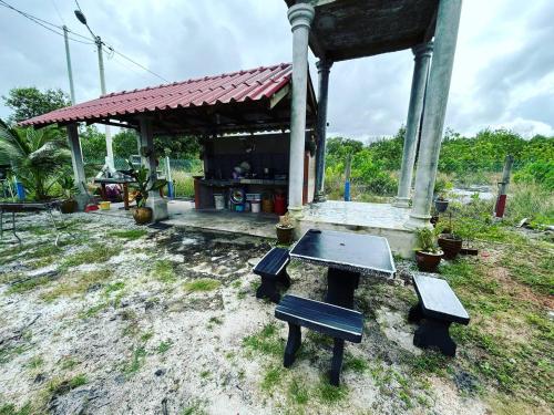 a picnic table and benches in front of a building at Mahasa Penarik Homestay in Kampong Ru Sepuloh