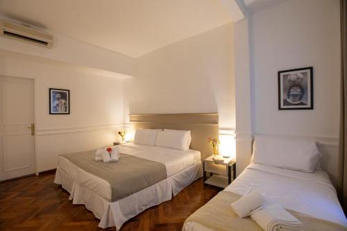 Duas camas num quarto com paredes brancas e pisos em madeira em El Misti Hotel Buenos Aires Centro em Buenos Aires