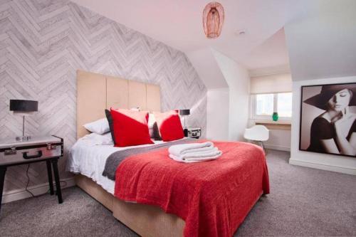 1 dormitorio con cama con almohadas rojas y manta roja en The Exquisite Manchester Abode - Parking, en Mánchester