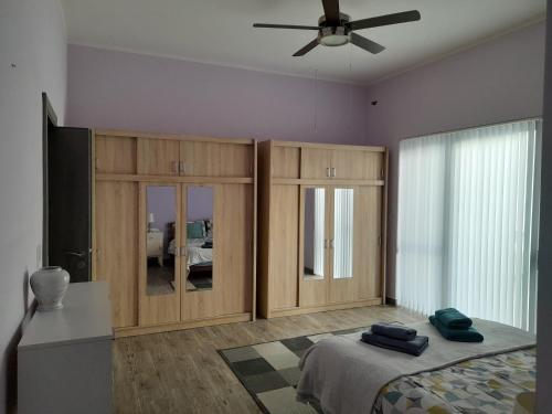 a bedroom with wooden cabinets and a bed and a ceiling fan at Spacious and Modern Apartment Near to the Sea in St Paul's Bay