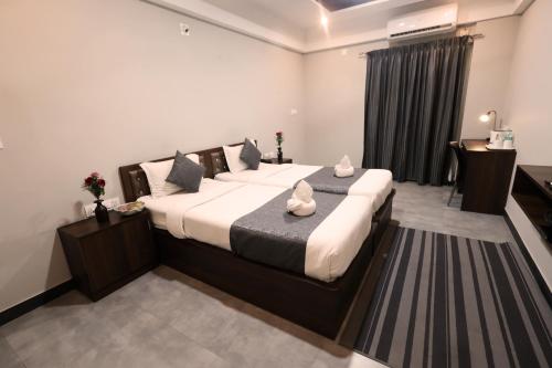 a bedroom with a large bed with white sheets and pillows at Royale Sapphire Suites Whitefield Main Rd, KR Puram in Bangalore