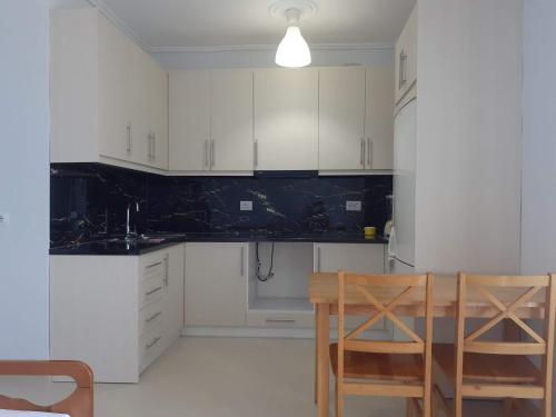 - une cuisine avec des placards blancs, une table et des chaises dans l'établissement Angels apartment, à Lukovë