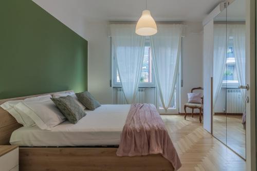 a bedroom with a bed with white sheets and windows at Como Borghi Apartment by Wonderful Italy in Como