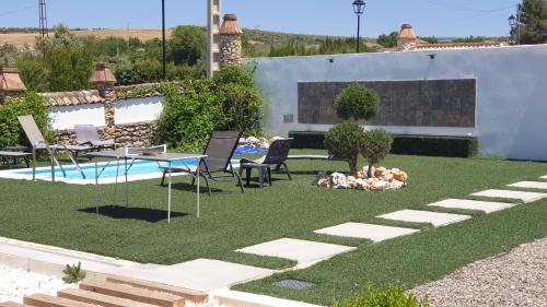 un jardín con mesa, sillas y piscina en Villa Minerva, en Arriate