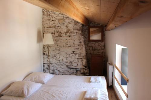 um quarto com uma cama branca numa parede de pedra em Hameau Bechetoile em Burdignes