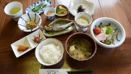 a wooden table with bowls of food on it at Shikisai no Sato Manyu in Kirishima