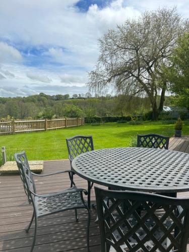 a table and chairs on a wooden deck with a yard at Meadow View in Mayfield