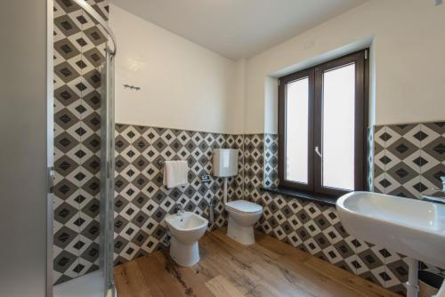 a bathroom with a sink and a toilet and a window at La Blave Rooms in Mortegliano