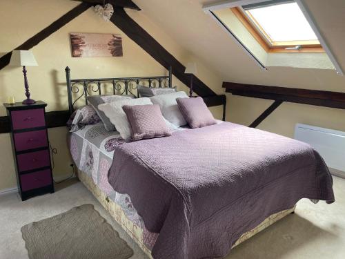 um quarto com uma cama com lençóis roxos e uma janela em Chambres d'Hôtes de la forge em Oradour-Saint-Genest