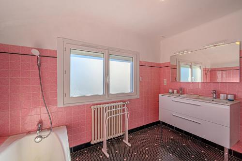 ein rosafarbenes Bad mit einem Waschbecken und einem Spiegel in der Unterkunft Demeure de Kérével in Plonéis