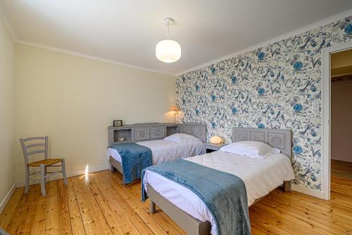 2 Betten in einem Zimmer mit blauen und weißen Tapeten in der Unterkunft Demeure de Kérével in Plonéis