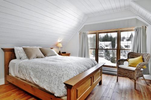 a bedroom with a bed and a window at Chalet 9023 Chemin des Alpages by Les Chalets Alpins in Stoneham