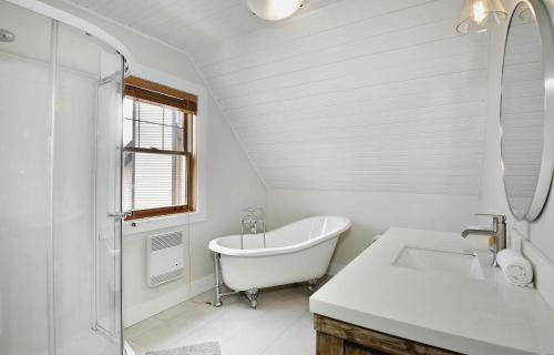 a white bathroom with a tub and a sink at Chalet 9023 Chemin des Alpages by Les Chalets Alpins in Stoneham