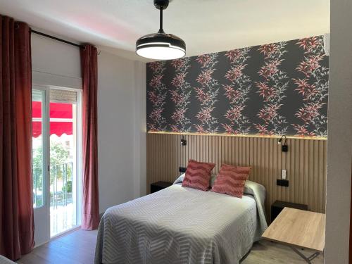 1 dormitorio con 1 cama con papel pintado negro y rojo en Hostal Calderón de la Barca, en Zalamea de la Serena