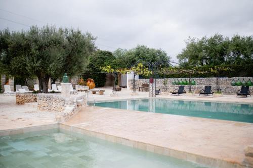 a swimming pool with chairs and trees in the background at Casina dei Preti in Conversano