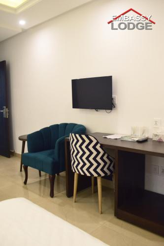 a room with a desk and a chair and a tv at Embassy Lodge in Islamabad