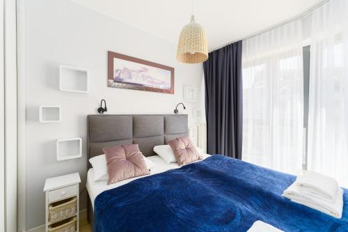 a bedroom with a bed with blue sheets and pink pillows at Międzyzdroje Horyzont - Apartament z Klimatyzacją i Balkonem by Renters in Międzyzdroje