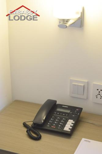 a black phone sitting on top of a desk at Embassy Lodge in Islamabad