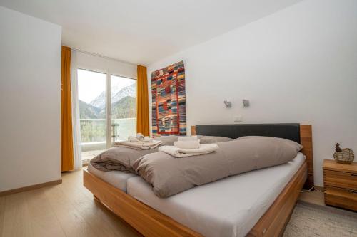 ein Schlafzimmer mit einem großen Bett und einem großen Fenster in der Unterkunft Chasa Miramunt 6 in Scuol