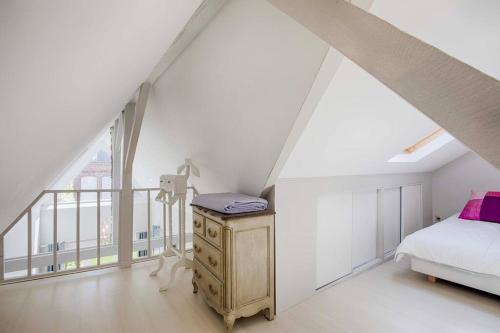 a bedroom with a bed and a dresser in a attic at La Villa du Figuier Deauville quartier de l'église in Deauville