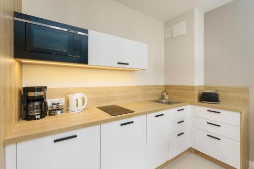 a kitchen with white cabinets and a microwave at Bel Mare 210C by Renters in Międzyzdroje