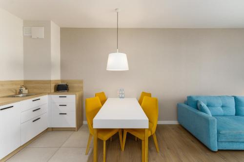 a kitchen and dining room with a white table and yellow chairs at Bel Mare 210C by Renters in Międzyzdroje